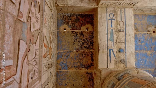 Medinet Habu temple ceiling with painted winged goddess Nut in blue and gold colors with hieroglyphs in Luxor Egypt, astronomical decorations and repeated deity figures