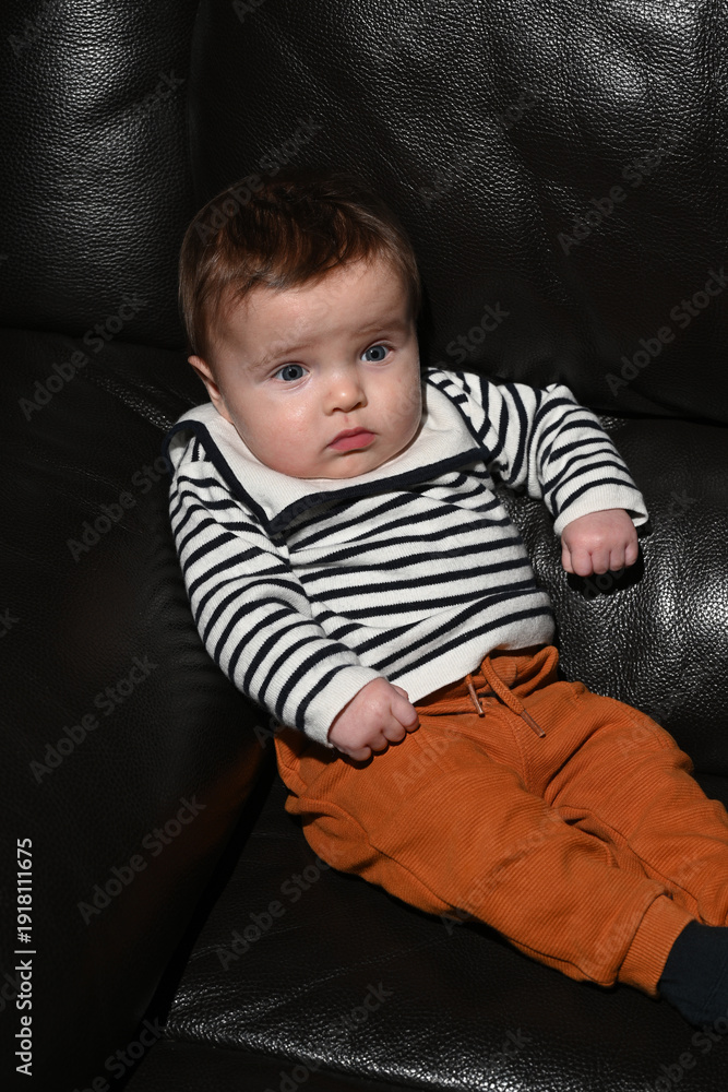 Fototapeta premium close-up of a young child wearing a sailor shirt sitting on a black sofa