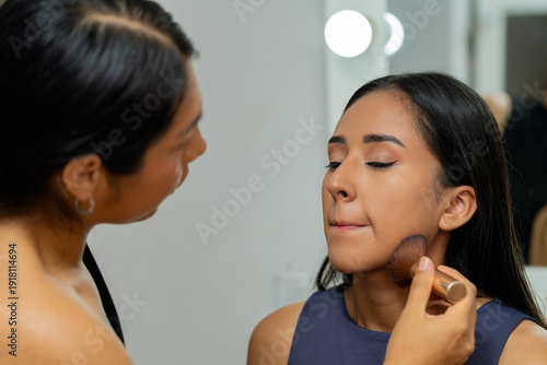 Fotografie Professional makeup artist applying cosmetics to latina woman
