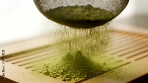 Close up of green powder falling in slow motion on wood or Close up of powder being sifted onto a surface