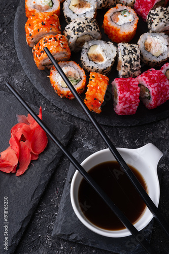 different sushi rolls set with fish beautiful served  at black dishes at black table. top view