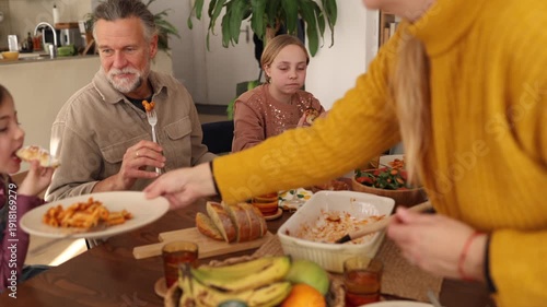 Grandparents, parents, and grandchildren gather around a dining table, sharing a delicious meal and creating lasting memories in a warm and inviting home setting