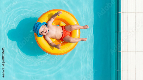 Happy baby smiling and relaxing in a bright yellow infant swim ring floating on clean turquoise pool water top down view, for summer vacation ads, poolside baby happiness content