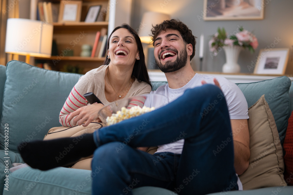 Obraz premium Happy young couple laughing watching tv at home