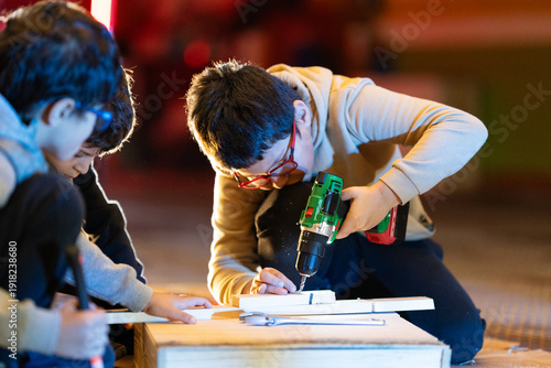 Children learning carpentry skills using power tools