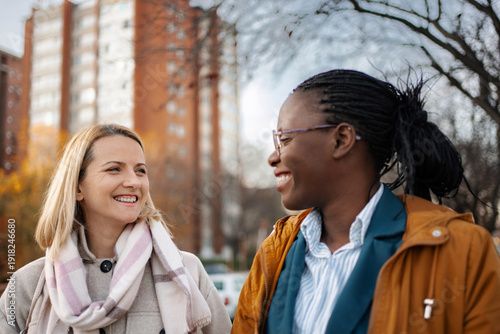Wallpaper Mural Two diverse adult women friends smiling and talking outdoors Torontodigital.ca