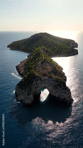 Natural arch on a rugged island surrounded by sparkling blue ocean.