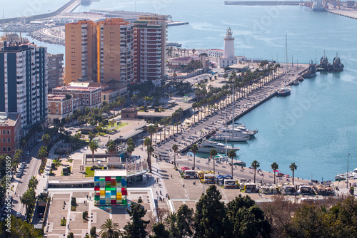 Malaga Spain high angle view of the Muelle Uno waterfront promenade with the Centre Pompidou glass cube and La Farola de Malaga lighthouse tower at the city harbor in La Malagueta.