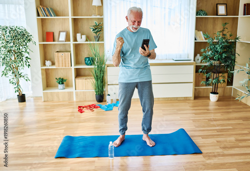 Wallpaper Mural Senior man exercise stretching or doing yoga at home, health care and active seniors concept, using a mobile phone Torontodigital.ca