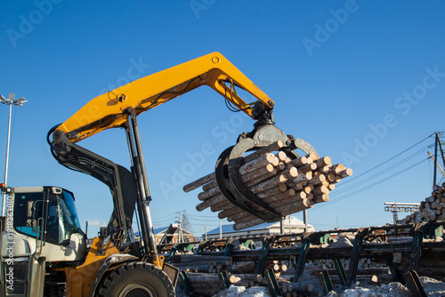 Loading logs with a special loader.Timber products warehouse on a specialized site.