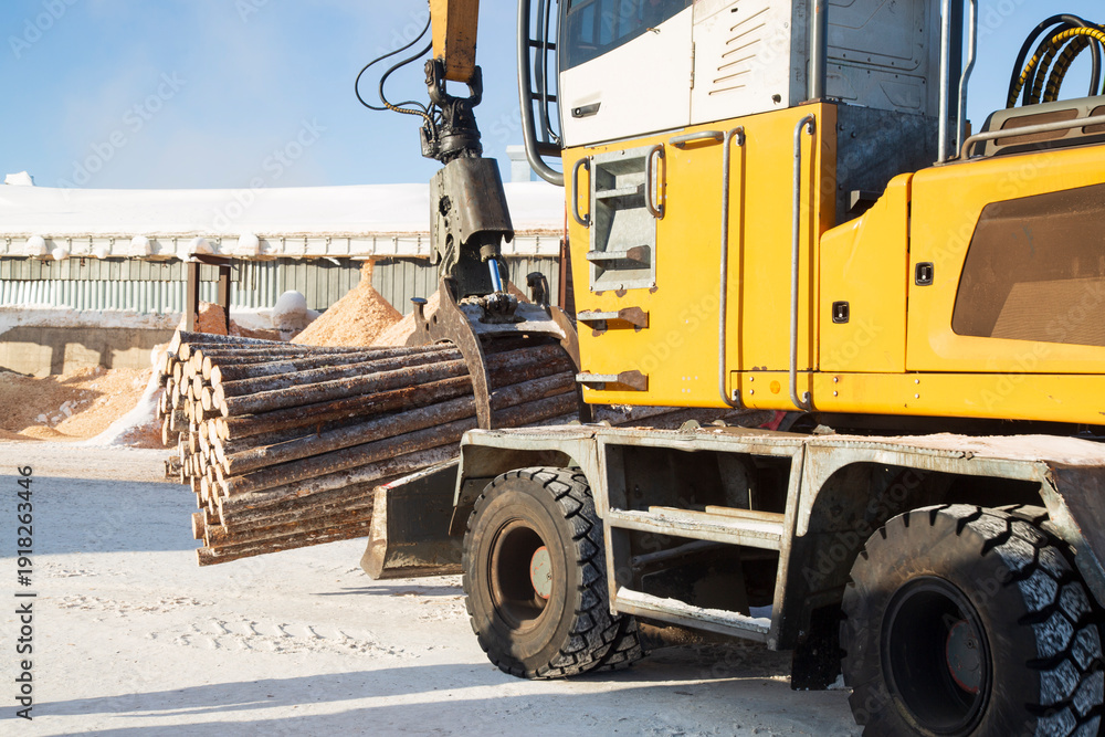 Obraz premium Loading logs with a special loader.Timber products warehouse on a specialized site.