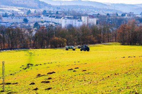 Wallpaper Mural Tractor with hay bales in a bright green field with a town in the background Torontodigital.ca