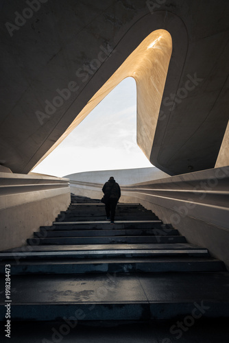 Person walking up in the stairs towards open bright space. The way forward