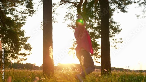 Woman walking in park in summer among trees, raising arms twirling joyfully. Slow motion. Woman's happiness in nature. Happy woman enjoying forest. Girl hiking through forest, relaxing in nature.