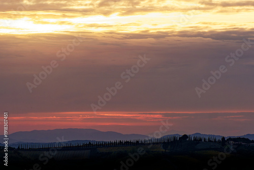 Wallpaper Mural Golden sunset over rolling hills of Tuscany, Italy, iconic cypress trees silhouetted against dramatic sky with layered mountains in the background Torontodigital.ca