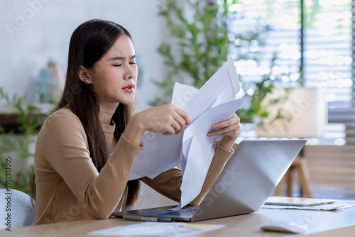 Businesswoman angry throwing papers over the herself in office when job fail. Serious woman working with laptop sitting at table at office