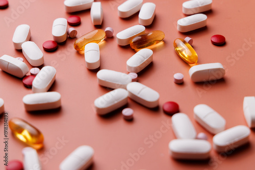 Scattered medical pills of various sizes and colors on a cream gradient background for clinical treatment and health supplement ads.
