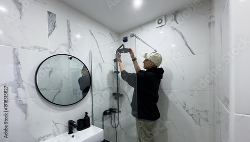 Professional handyman working in shower booth indoors, space for text