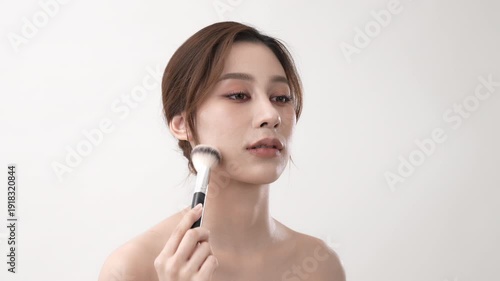 Wallpaper Mural Beauty concept of 4k Resolution. Asian woman is applying her makeup with a brush on a white background. Torontodigital.ca