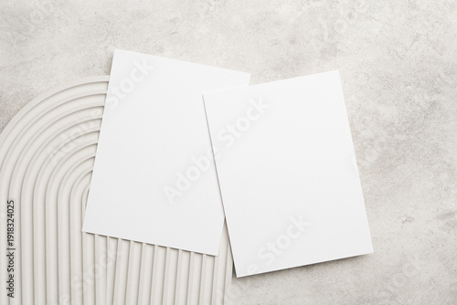 Wedding invitation card mockup with two blank white cards on a textured surface with curved lines, ideal for design and personalization purposes