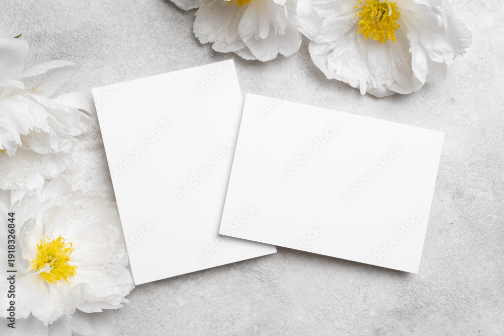 Obraz premium Blank wedding invitation cards mockup with white peony flowers, two cards front and back sides with copy space for design presentation
