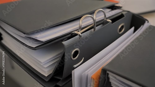 A close-up of a filled grey binder, with metallic rings and open