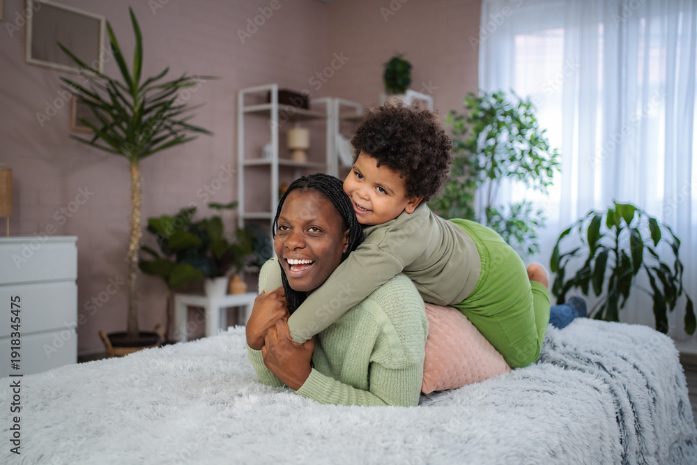 Fototapeta premium African American mother and child playing on bed