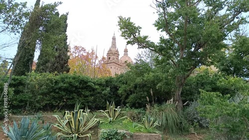Distant view of the National Palace of Montjuic from a lush green garden in Barcelona