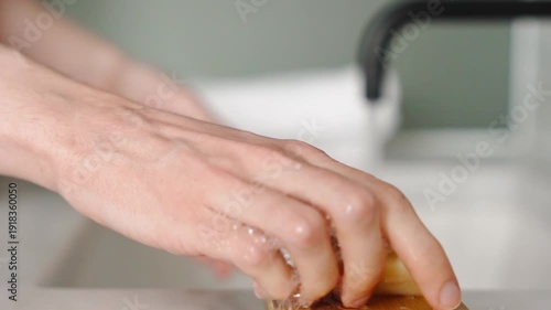 Hands pick up bar soap, lather and rub skin under running water, then place soap into dish during slow motion hygiene routine at sink