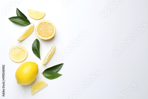 Foto Fresh lemon fruits and green leaves on white background, flat lay