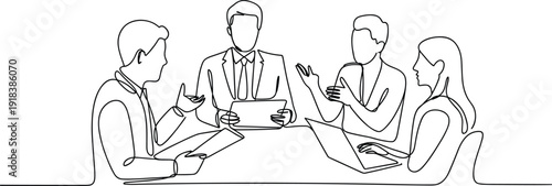 Four people in business attire discussing around a table with laptops and documents
