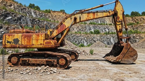 Rusty Excavator Abandoned in a Rocky Quarry on a Bright Sunny Day, Heavy Construction Equipment