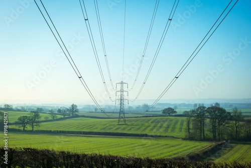 Sun setting behind the electric power lines running from Dungeness power station on the Kent coast south east England UK