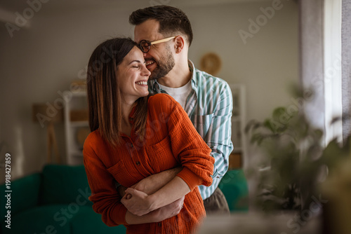 Bilde på lerret Happy couple embracing, smiling, and sharing a loving moment at home