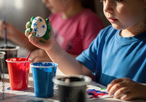 Child holding a decorated easter egg with paint and colorful cups nearby
