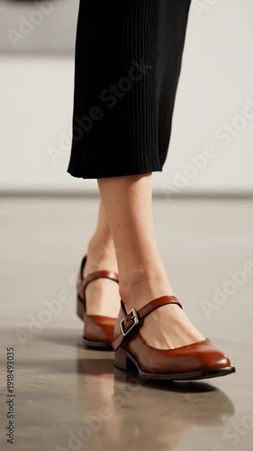 A woman's legs and feet are seen walking in stylish brown shoes on a polished