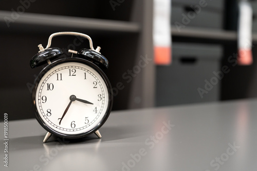 Classic Black Alarm Clock on Office Desk for Time Management Concept. symbolizing morning routines, deadlines, productivity, and the importance of punctuality in a professional working or studying env