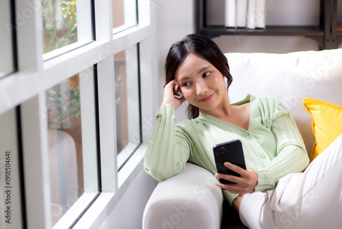 Wallpaper Mural Young asian businesswoman looking smartphone smiling and relax sitting on sofa in living room at home, cheerful woman watching smart phone sitting on couch in home, lifestyle and communication. Torontodigital.ca