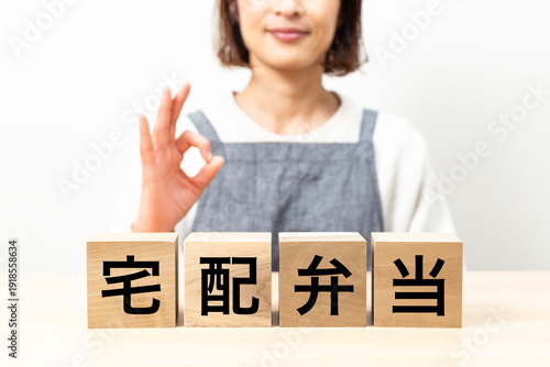 「宅配弁当」と書かれたブロックとエプロン姿の女性