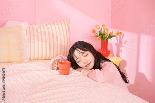 ピンク背景の部屋でリラックスするアジアの若い女性のポートレート