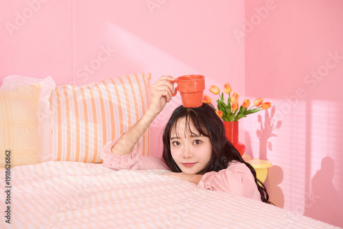 ピンク背景の部屋でリラックスするアジアの若い女性のポートレート