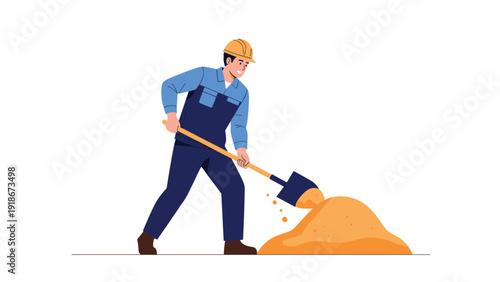 Hardworking construction worker in a blue uniform and yellow hard hat digging a pile of sand with a shovel at a building site.