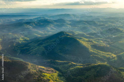 Aerial view of rolling green mountains with sunlight casting shadows landscape hills