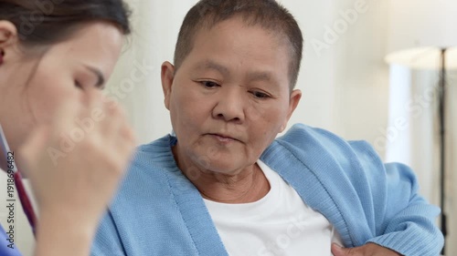 Portrait of a senior elderly gray-haired woman patient in medical office talking to a female friendly nurse sitting on couch in clinic and having consultation during exam. 4k video