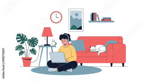 Young man sitting on the floor works on a laptop at home while a white cat sleeps on a comfortable red sofa nearby.
