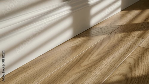 Seamless abstract looping motion focusing on the repetitive sharp shadow lines cast across the clean white molding and the horizontal engineered wood planks pattern, focusing, transition