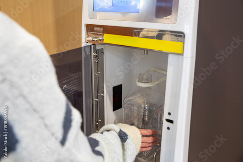 スーパーのウォーターサーバーで水を汲む女性