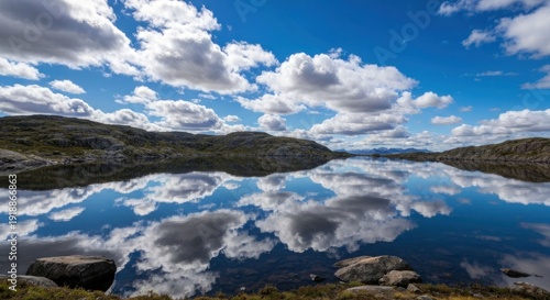 Lake reflects sky, rocky shores, fluffy clouds
