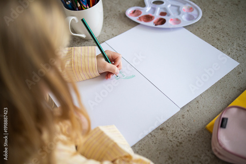 Over Shoulder View of Young Girl Drawing with Pencil at Home.