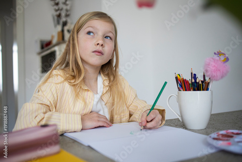 Young Girl Concentrating While Drawing or Doing Homework at Home.